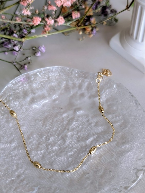 Złota błyszcząca bransoletka z diamentowanymi baryłkami i splotem ankier. Długość 16-19 cm, średnica 2,9 mm, zapięcie karabińczyk. Elegancka złota biżuteria.